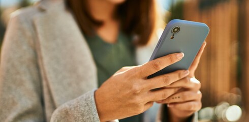 Young hispanic girl smiling happy using smartphone at the city.