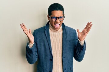 Young handsome hispanic man wearing elegant clothes and glasses celebrating mad and crazy for...