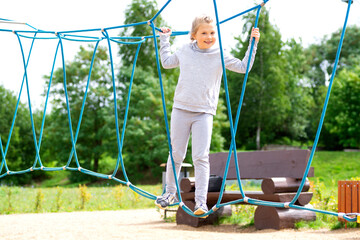 Little girl climbing in an adventure park. The girl loves to climb in the adventure of the rope course. Little girl on the rope obstacle course