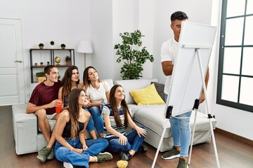 Group of young hispanic friends smiling happy playing draw game at home.
