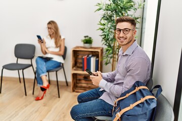 Two hispanic person smiling happy using smartphone at waiting center