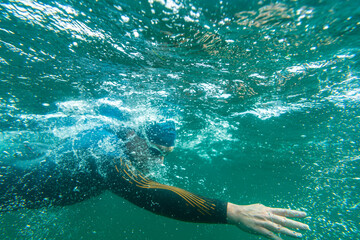 Athlete in a wetsuit swims in a lake