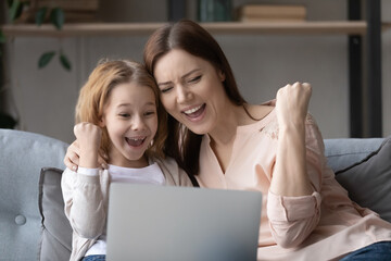 Overjoyed young Caucasian mother and teen daughter feel euphoric win lottery online on laptop....