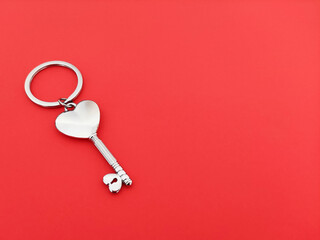 Silver heart shaped key on red background
