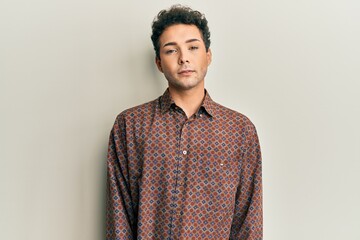 Handsome hispanic man wearing casual clothes relaxed with serious expression on face. simple and...