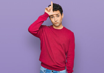 Young handsome man wearing casual clothes making fun of people with fingers on forehead doing loser gesture mocking and insulting.