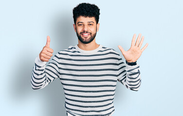 Young arab man with beard wearing casual striped sweater showing and pointing up with fingers number six while smiling confident and happy.