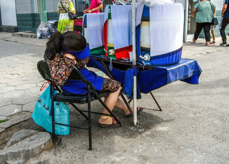 Obraz na płótnie Canvas A sleeping girl on a chair from fatigue. Seller of cold drinks.