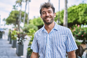 Young hispanic man smiling happy standing at the city.