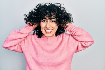 Young middle east woman wearing casual clothes smiling pulling ears with fingers, funny gesture....