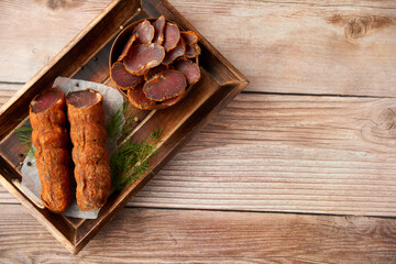 Homemade jerked dried meat or biltong with spices on a wooden background. Beer snack concept. Selective focus, copyspace.