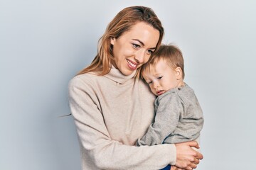 Young caucasian woman holding and hugging her son with love. Family of two bonding together. Mother holding infant toddler