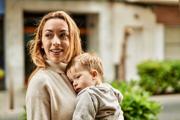 Obraz premium Beautiful family of mother and baby son hugging and bonding together with love. Parent and toddler outdoors