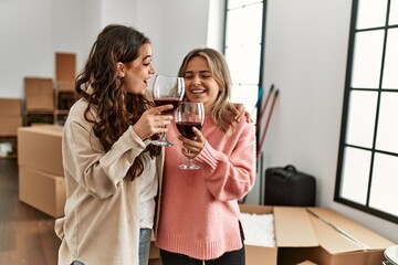 Young couple smiling happy toasting with red wine at new home