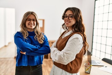 Two business workers woman smiling happy standing with arms crossed gesture at the office.