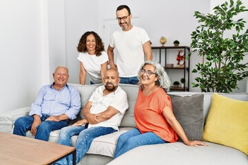 Group of middle age friends smiling happy sitting on the sofa at home.