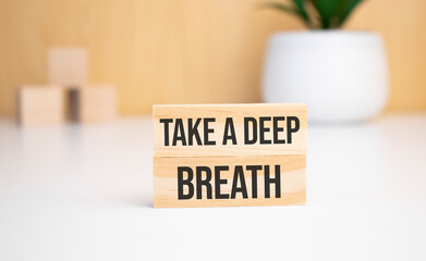 On a light background, wooden cubes and a wooden block with the text Take a deep breath. View from...