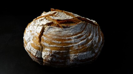 Round loaf of freshly baked bread in a dark environment