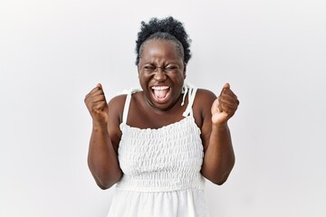 Fototapeta premium Young african woman standing over white isolated background excited for success with arms raised and eyes closed celebrating victory smiling. winner concept.
