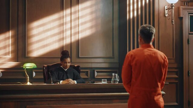 Court of Law and Justice Trial Proceedings: Law Offender in Orange Jumpsuit is Questioned and Giving Testimony to Judge, Jury. Criminal Denying Charges, Pleading, Inmate Denied Parole.