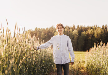 Young handsome guy walks on a wheat field