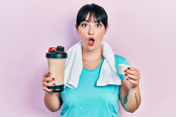 Young hispanic woman wearing sportswear holding water bottle afraid and shocked with surprise and amazed expression, fear and excited face.