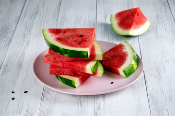 Close-up of sliced pieces of ripe red watermelon on a light wooden surface. Healthy food concept, summer food. Selective focus.
