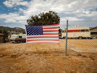 American flag attached to a chain link fence in a rural impoverished area