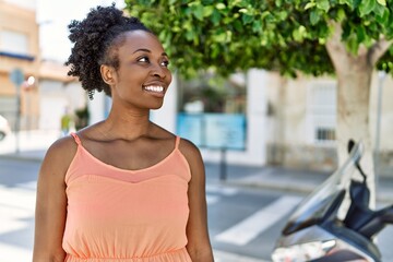Fototapeta na wymiar Young african american woman smiling happy at the city on a summer day