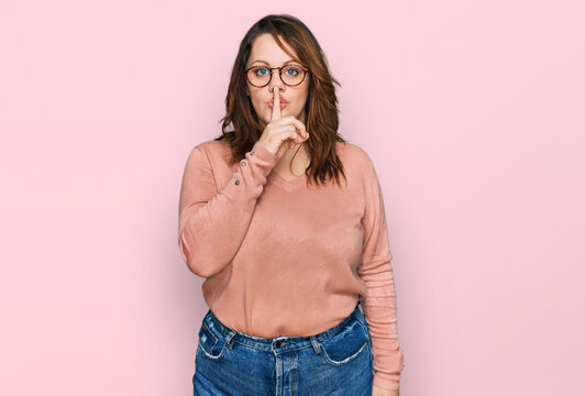Young plus size woman wearing casual clothes and glasses asking to be quiet with finger on lips. silence and secret concept.