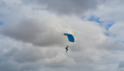 Skydiving as an exciting but extreme sport. People descend on blue parachutes