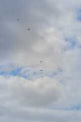 Skydiving as an exciting but extreme sport. People descend on blue parachutes