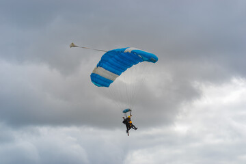Skydiving as an exciting but extreme sport. People descend on blue parachutes