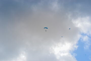Fototapeta na wymiar Skydiving as an exciting but extreme sport. People descend on blue parachutes