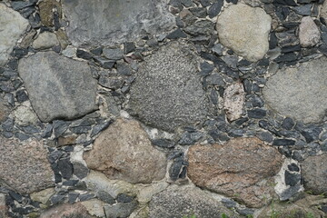 A wall of cut stone. Granite. Dough. Surface.