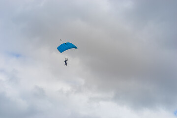 Skydiving as an exciting but extreme sport. People descend on blue parachutes