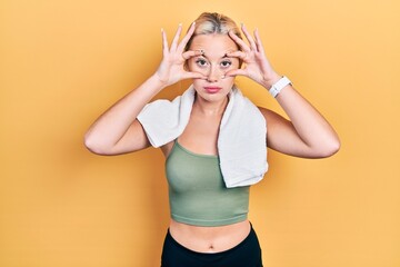 Young blonde girl wearing sportswear and towel trying to open eyes with fingers, sleepy and tired for morning fatigue