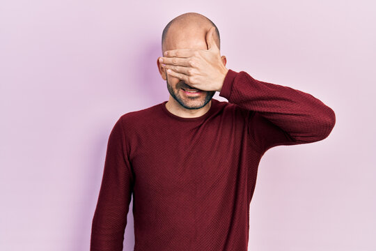 Young bald man wearing casual clothes smiling and laughing with hand on face covering eyes for surprise. blind concept.