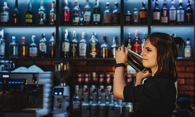 Portrait of young attractive woman bartender Making Cocktail Using Shaker in bar