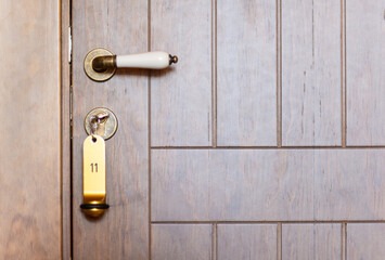 Close-up of a wooden vintage hotel door with number eleven in the keychain.