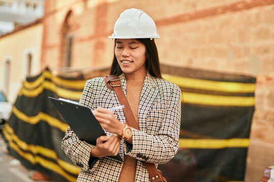 Young asian architect woman smiling happy writing on clipboard at the city.
