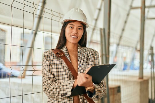 Young asian architect woman smiling happy writing on clipboard at the city.