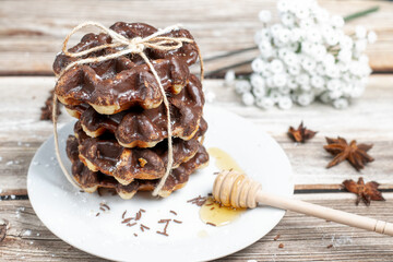 Chocolate waffles with honey on a wooden table