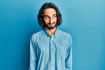 Young hispanic man wearing casual clothes smiling looking to the side and staring away thinking.