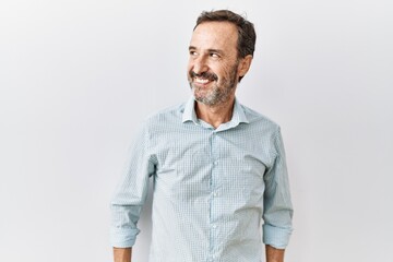 Middle age hispanic man with beard standing over isolated background smiling looking to the side and staring away thinking.