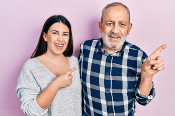 Hispanic father and daughter wearing casual clothes cheerful with a smile on face pointing with hand and finger up to the side with happy and natural expression