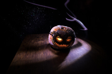 Halloween pumpkin smile and scary eyes for party night. Close up view of scary Halloween pumpkin with eyes glowing inside at black background