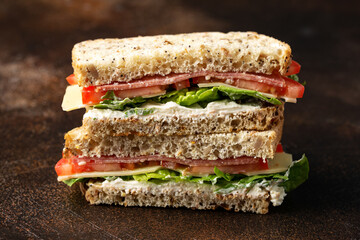 Sandwiches with lettuce, slices of fresh tomatoes, salami and cheese.