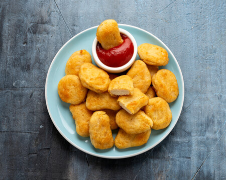 Vegetarian vegan crispy nuggets with ketchup on blue plate