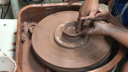 Hands of mother and child shaping clay on a ceramics pottery wheel